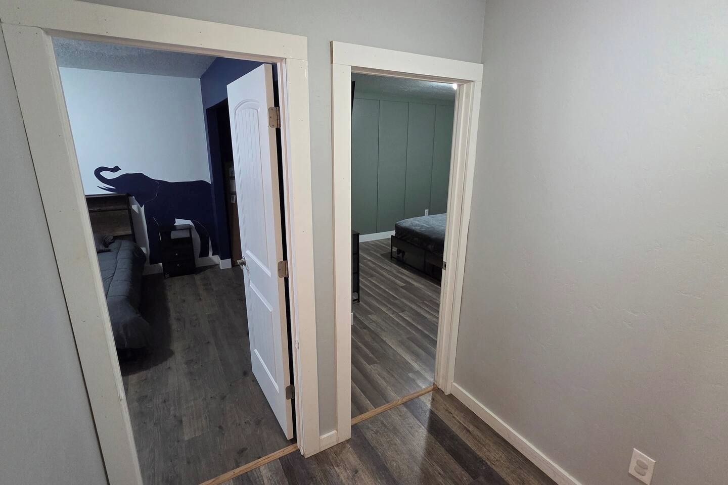 Un corridoio con una porta che dà su una camera da letto, con un letto e una cassettiera.