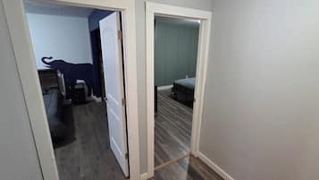 Un corridoio con una porta che dà su una camera da letto, con un letto e una cassettiera.