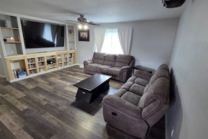 A living room with a flat-screen TV, two sofas, a coffee table, and a bookshelf. - Entire Upper Floor by ISU • Fenced Yard • Dogs OK (Pocatello)