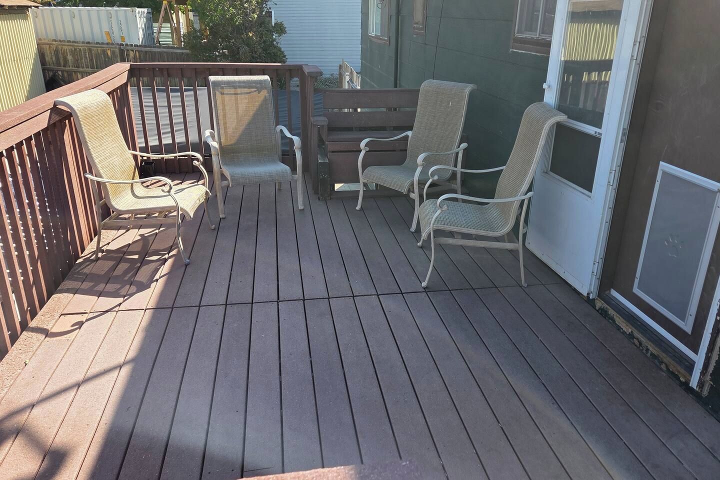 A wooden deck with outdoor furniture including chairs and a table.
