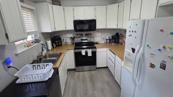 A compact kitchen with white cabinets, a microwave, a stove, and a refrigerator.