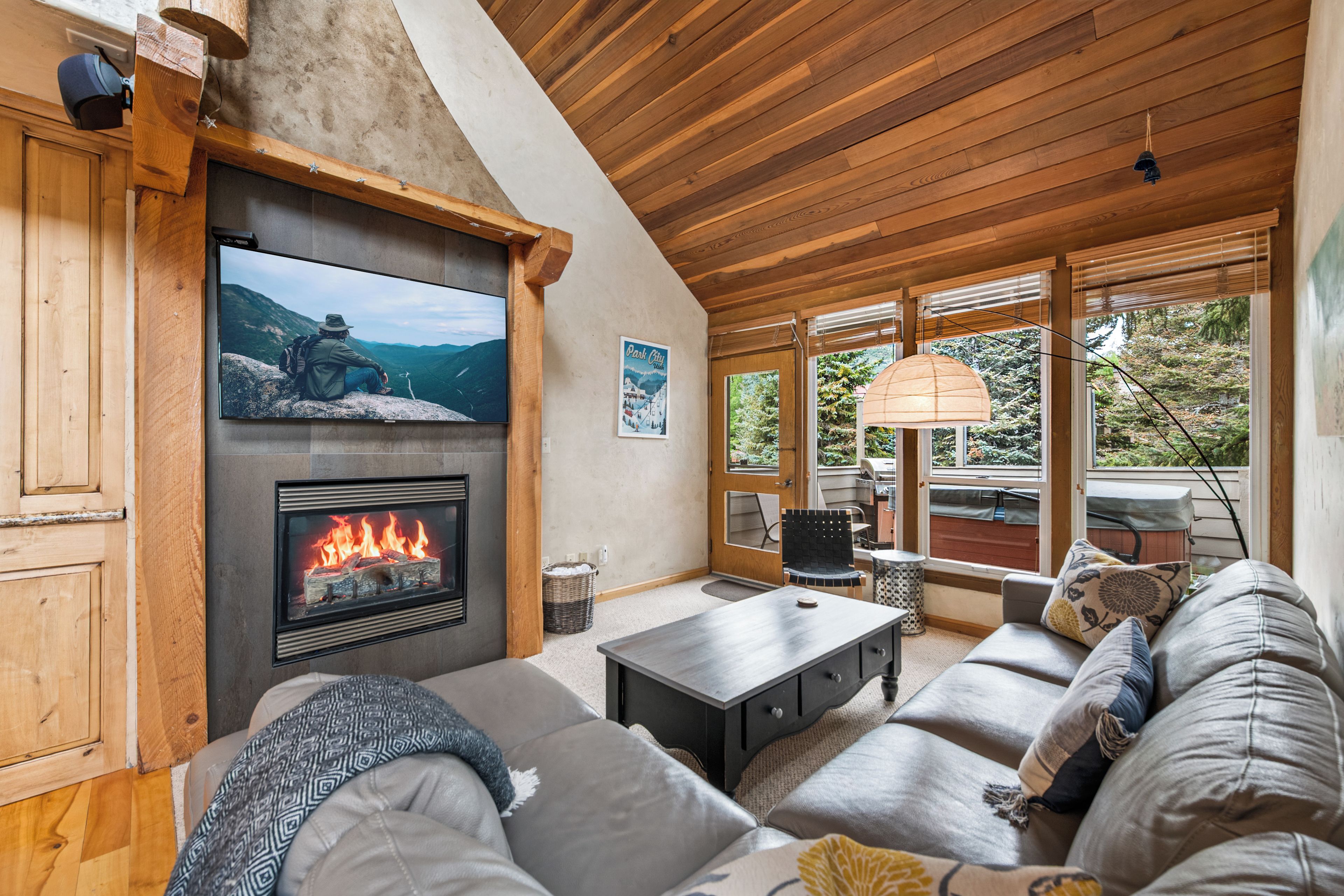 A cozy living room with a fireplace, a large TV mounted on the wall, and a comfortable seating area.
