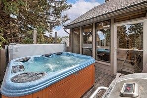 A hot tub with a wooden exterior, a glass-enclosed patio area, and a view of the surrounding trees. - Park City-Kings Heaven: Steps to Silver Star Lift /Hot Tub, XC Skiing & Golf (Park City)