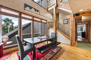 A spacious room with a dining table, chairs, and a bench. A staircase leads to an upper level. - Park City-Kings Heaven: Steps to Silver Star Lift /Hot Tub, XC Skiing & Golf (Park City)