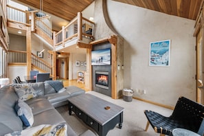 A spacious living room with a fireplace, a staircase, and a view of the outdoors. - Park City-Kings Heaven: Steps to Silver Star Lift /Hot Tub, XC Skiing & Golf (Park City)