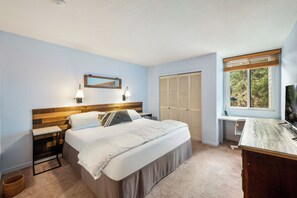 A bedroom with a bed, bedside tables, a desk, a chair, a wardrobe, a mirror, and a window with blinds. - Park City-Kings Heaven: Steps to Silver Star Lift /Hot Tub, XC Skiing & Golf (Park City)