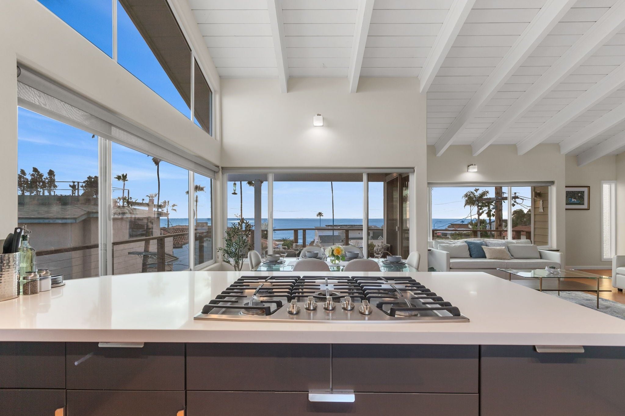 A modern kitchen with a large island, large windows, and a view of the ocean.
