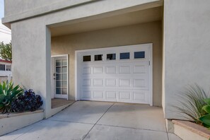 Un garage avec une porte blanche, un mur en béton et un petit hall d’entrée.