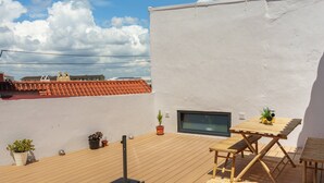 A rooftop terrace with a wooden deck, a table with chairs, and potted plants. - Stay at SuCaSa in Coimbra (Coimbra)