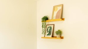 A small, neatly arranged bedroom with a bed, a bedside table, a lamp, and wall-mounted shelves with decorative items. - Stay at SuCaSa in Coimbra (Coimbra)