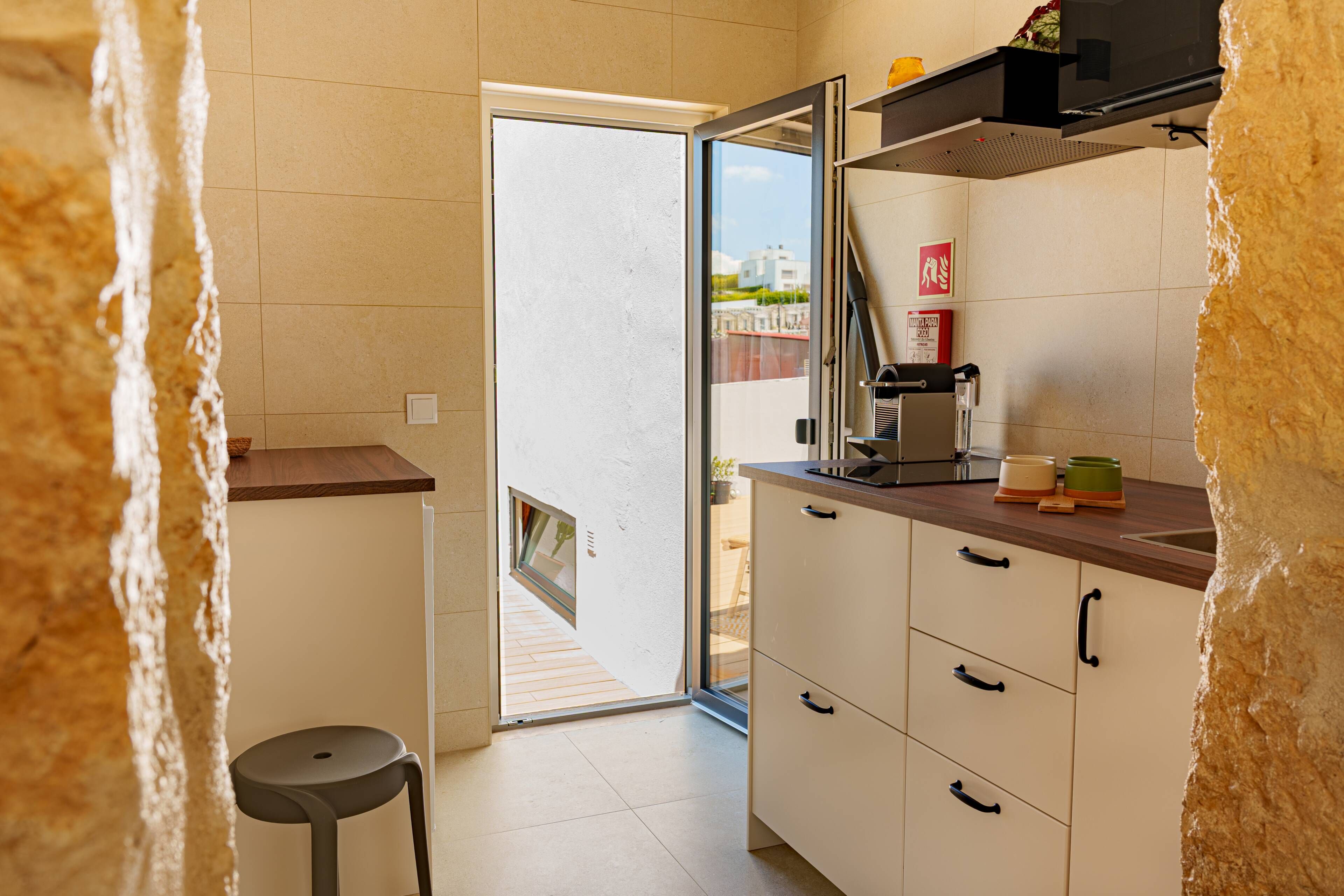 A kitchen with a built-in oven, a coffee machine, and a small refrigerator.