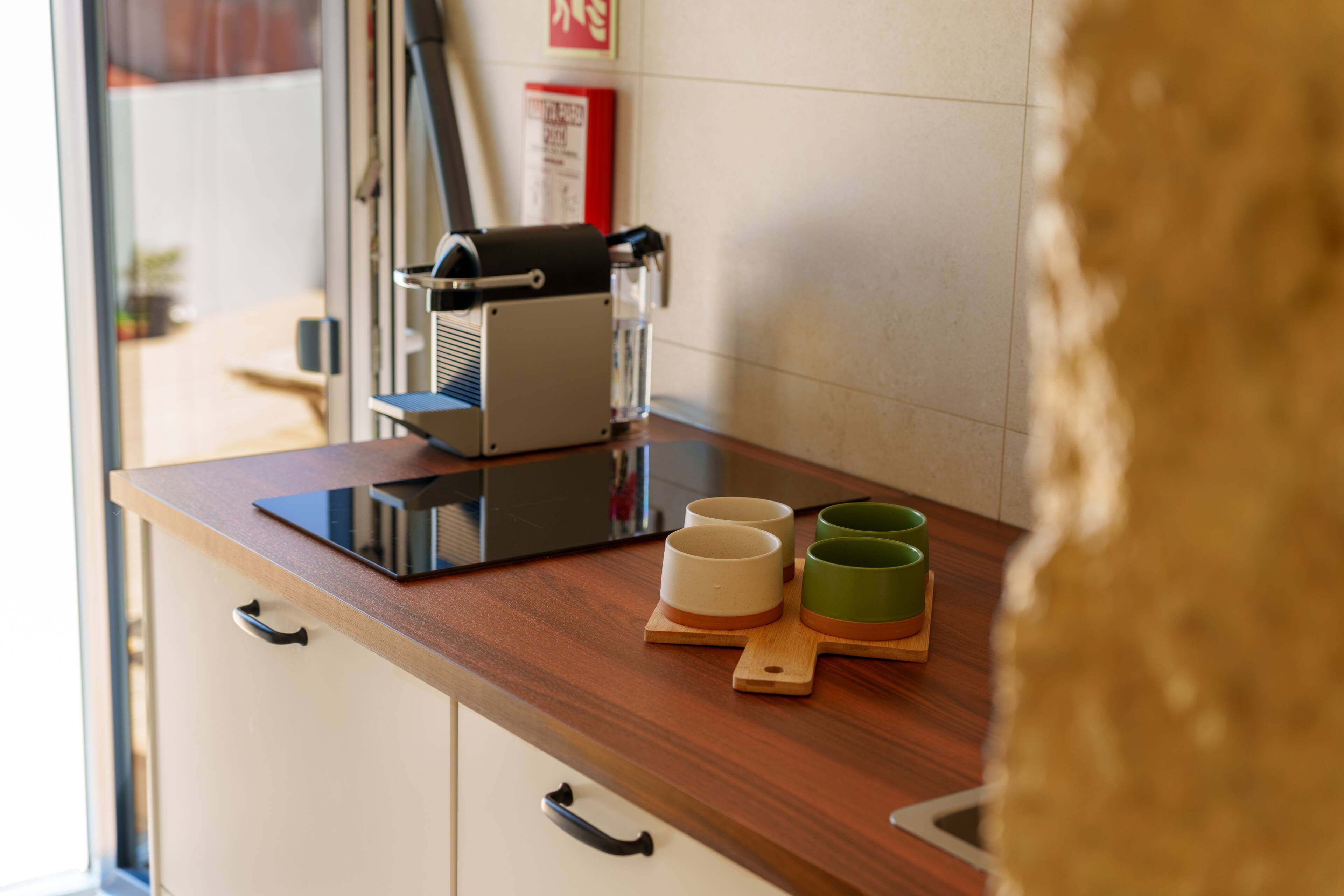 Un bancone cucina con una macchina da caffè, due tazze e una bottiglia d'acqua.