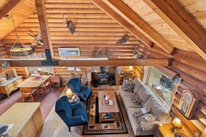 A log cabin interior with a dining area, seating, fireplace, and rustic decor. - Cozy Riverfront Log Cabin with Private Hot Tub (Bend)