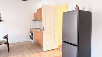 Una cocina compacta con refrigerador, estufa y armarios de madera.