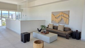 En moderne stue med sofa, sofabord og et stort vindue med udsigt over bybilledet.