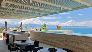 En tagterrasse med udendørs siddepladser, en pool og havudsigt.