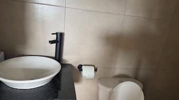 A bathroom with a white sink, black faucet, and a toilet.