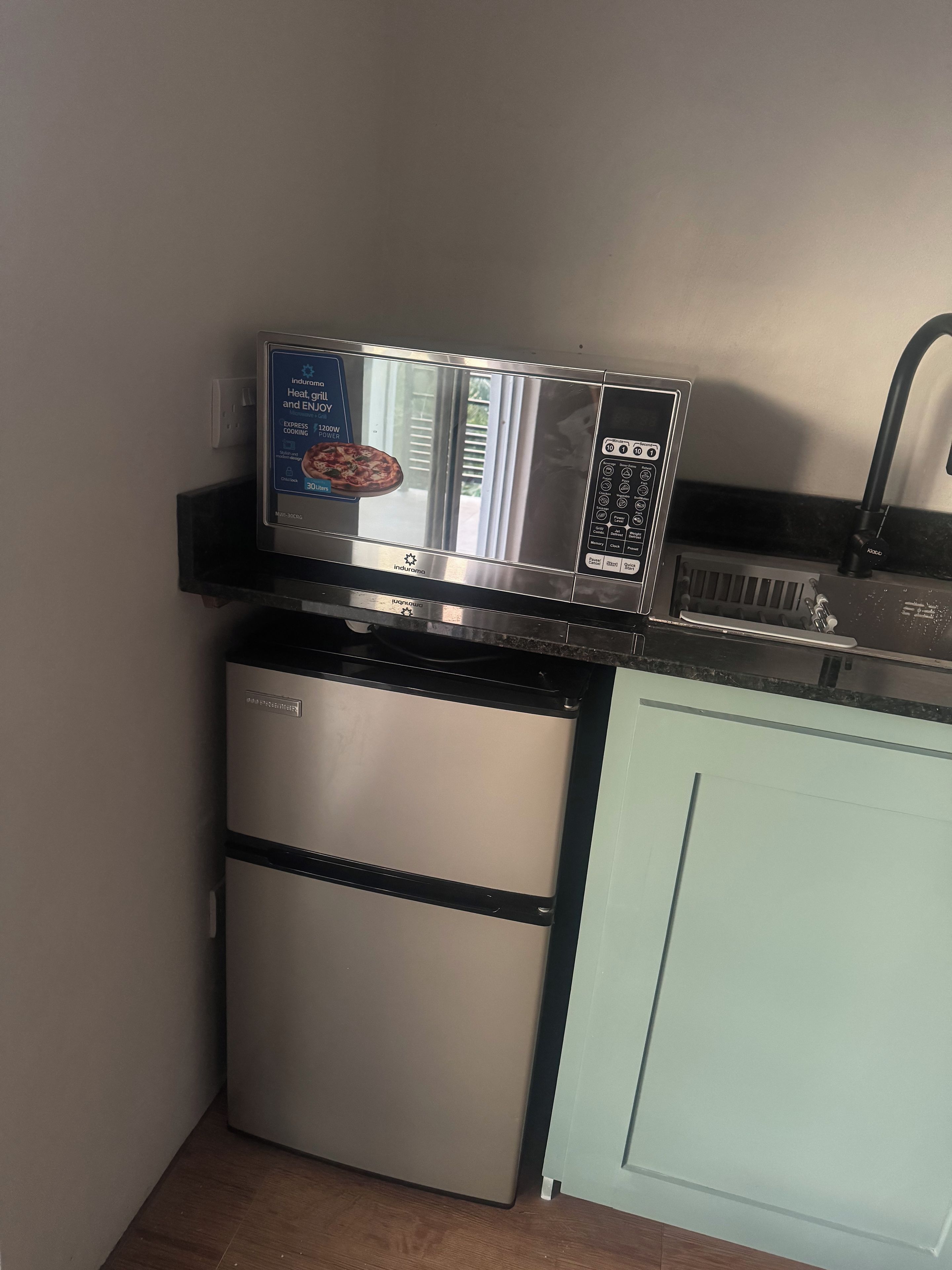 Cozinha compacta com micro-ondas, mini-geladeira e pia.