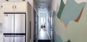 Ein schmaler Flur mit einer Küchenzeile links, inklusive einer Doppeltür-Kühlschrank und Schränken.