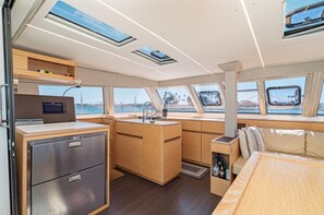A compact galley with a microwave, refrigerator, and wooden cabinets. - EXCLUSIVE OFFER! 46' Luxury Catamaran Yacht with free access to 5 Star Resort! (Key West)