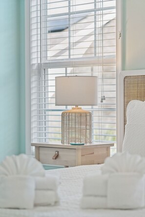 A bedroom with a bed, a bedside table with a lamp, and a window with blinds. - Seaglass! Folly 30 night Minimum Stay-Close to Beach & Town- (Folly Beach)