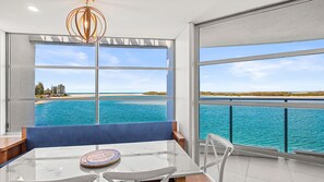 Ein moderner Essbereich mit freiem Blick auf das Meer und den Strand durch große Fenster.