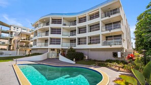 Un edificio residenziale a più piani con una piscina in primo piano.