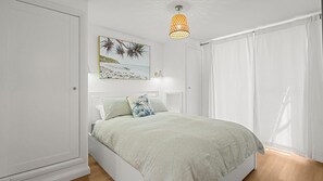 A bedroom with a bed, a painting, a lamp, and a window with curtains. - Pumicestone Chase Unit 11, 4 Maloja Ave, Caloundra (Caloundra)