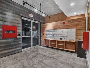 A modern interior with a glass door entrance, a red trash bin, and a wooden shelf unit with drawers. - Contemporary 2BR/2BA in downtown Orlando (Orlando)