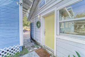 A house with a yellow door, a white picket fence, and a small garden area. - Historic Bungalow + Guest House • Patio & Grill (Tampa)