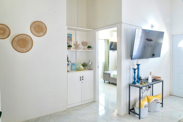 A room with a bed, a TV mounted on the wall, and a cabinet with decorative items.