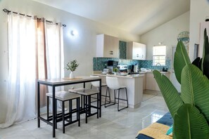 A modern kitchen with a central island, white cabinetry, and a backsplash with a geometric pattern.