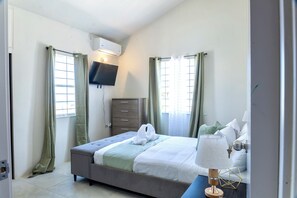 Un dormitorio con cama, cómoda, televisor y lámpara.