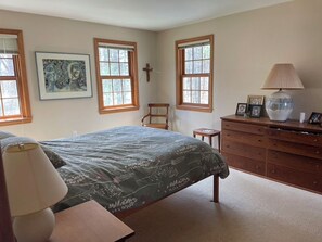 A bedroom with a bed, a dresser, a chair, a lamp, and framed pictures on the wall. - Spacious 4-bedroom house in charming Hanover with fitness room (Hanover)