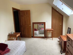 A bedroom with a bed, a wooden dresser, a nightstand, a mirror, and a door. - Spacious 4-bedroom house in charming Hanover with fitness room (Hanover)