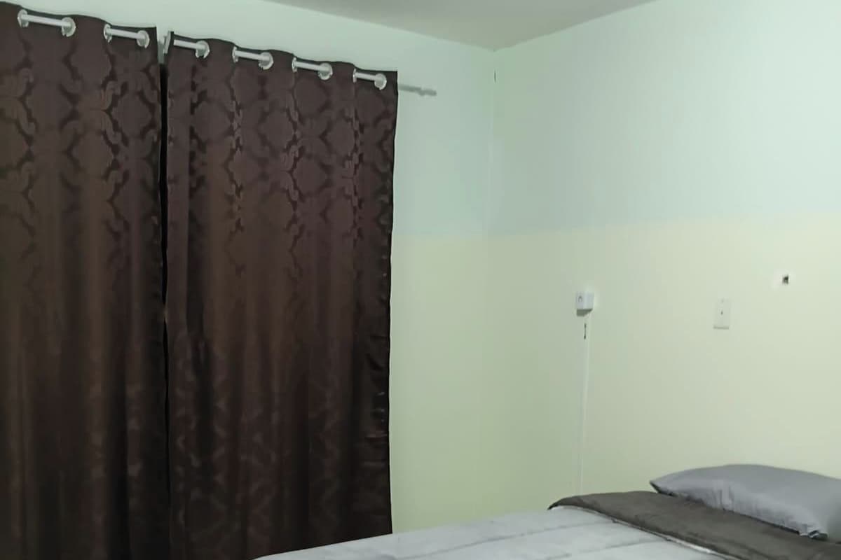 A bedroom with a bed, curtains, and a light switch on the wall.