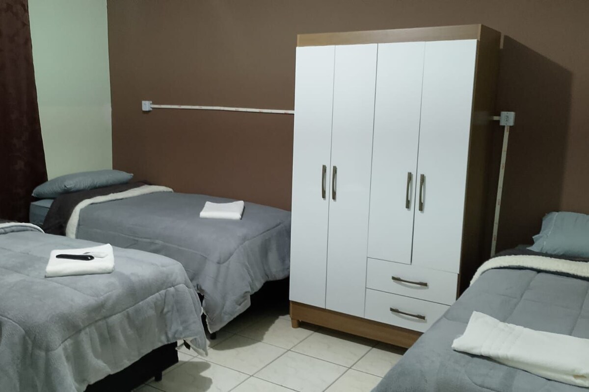 A hotel room with two single beds, a wardrobe, and a bedside table.