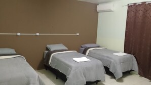 A room with two single beds, a brown wall, an air conditioning unit, and a curtain. - Hotel da Luz (Pinhão)