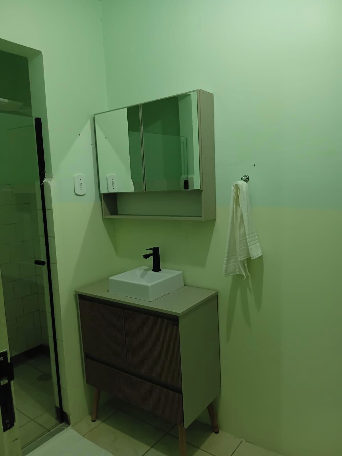 Ein Badezimmer mit einem weißen Waschbecken, einem Spiegel darüber und einem Handtuch an einem Haken.