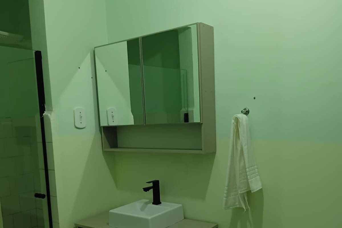 A bathroom with a white sink, a mirror above it, and a towel hanging on a hook.
