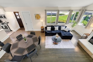 Ein modernes Wohnzimmer mit einer Eckcouch, einem Esstisch mit Stühlen und einer Küche im Hintergrund.