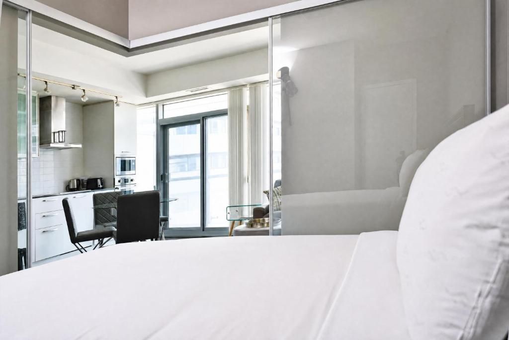 A modern hotel room with a bed, a desk, and a kitchenette.
