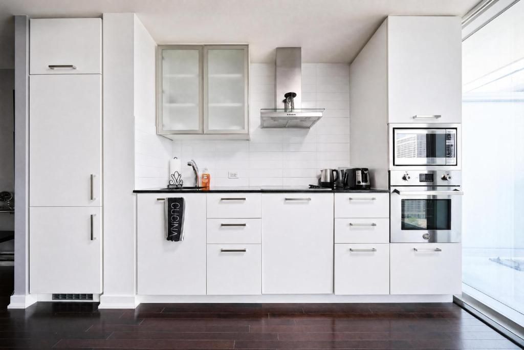 A modern kitchen with white cabinetry, a microwave, an oven, and a coffee maker.