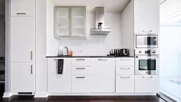 A modern kitchen with white cabinetry, a microwave, an oven, and a coffee maker.