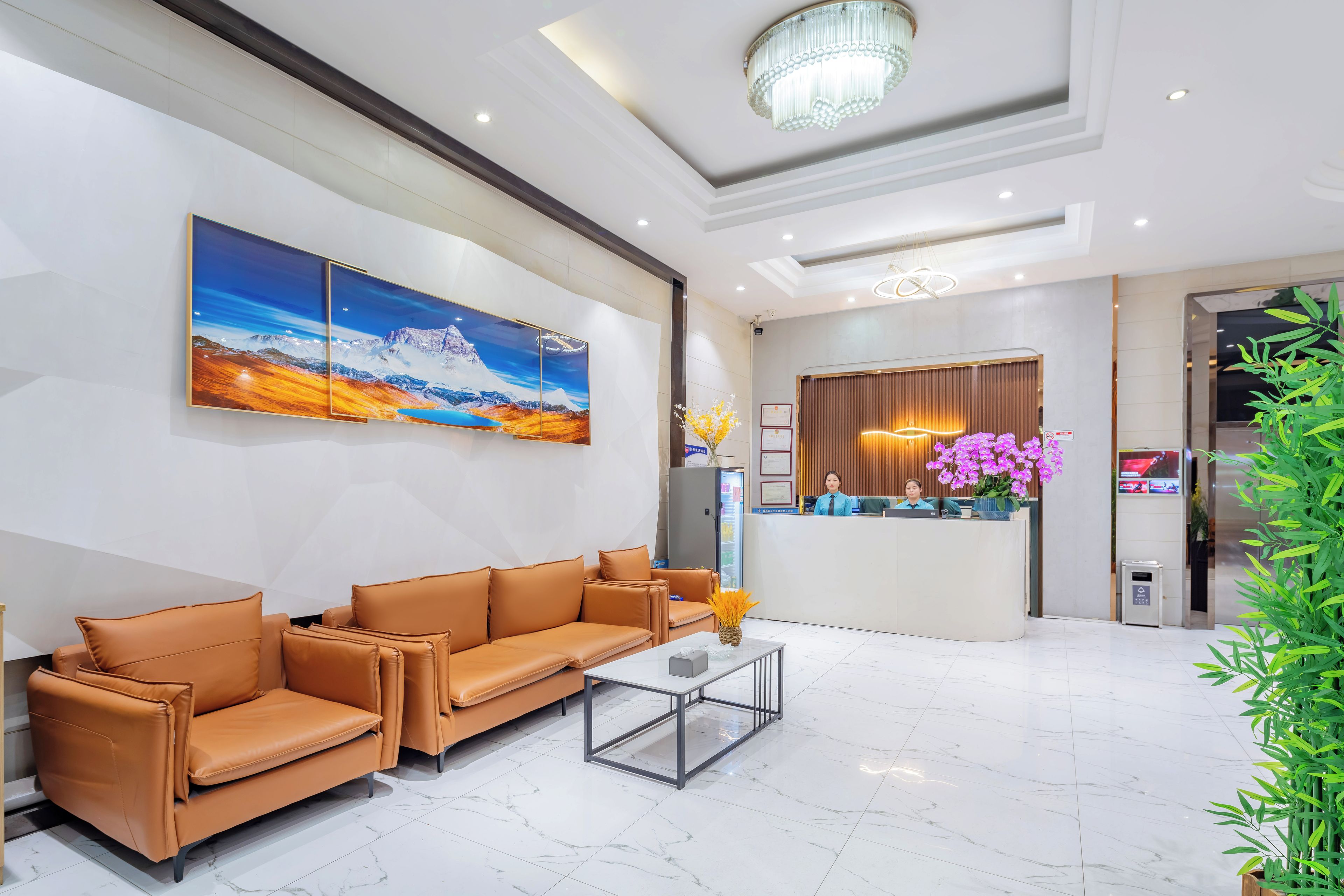 Un vestíbulo de hotel con una mesa de recepción, un cuadro grande, un conjunto de sofás y una mesa de centro.