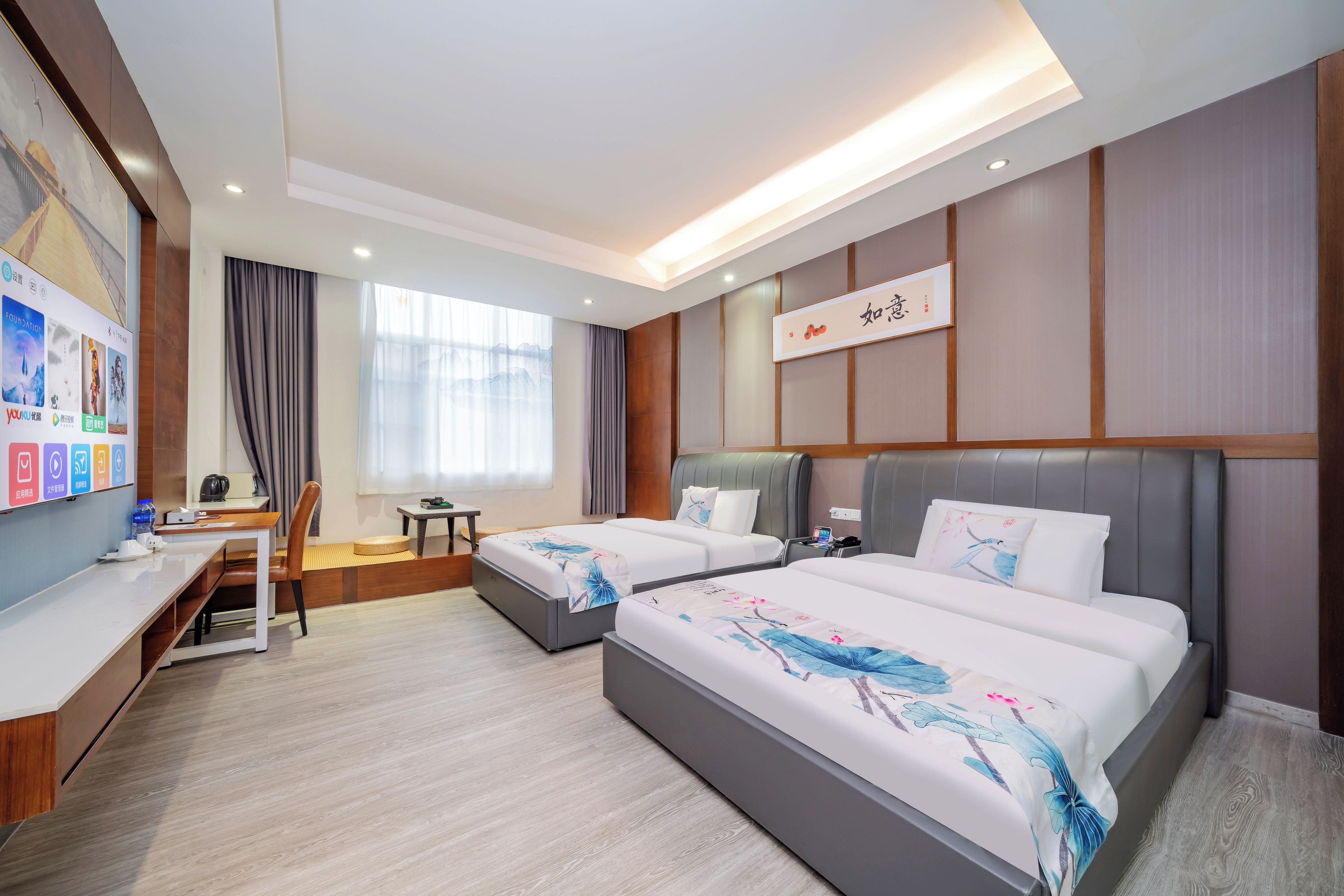A hotel room with two beds, a desk, a chair, a small table, and a large window with curtains.