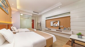 Ein Hotelzimmer mit zwei Betten, einem Fernseher, einem kleinen Tisch und einer Pflanze.