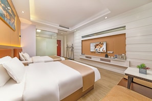 Ein Hotelzimmer mit zwei Betten, einem Fernseher, einem kleinen Tisch und einer Pflanze.