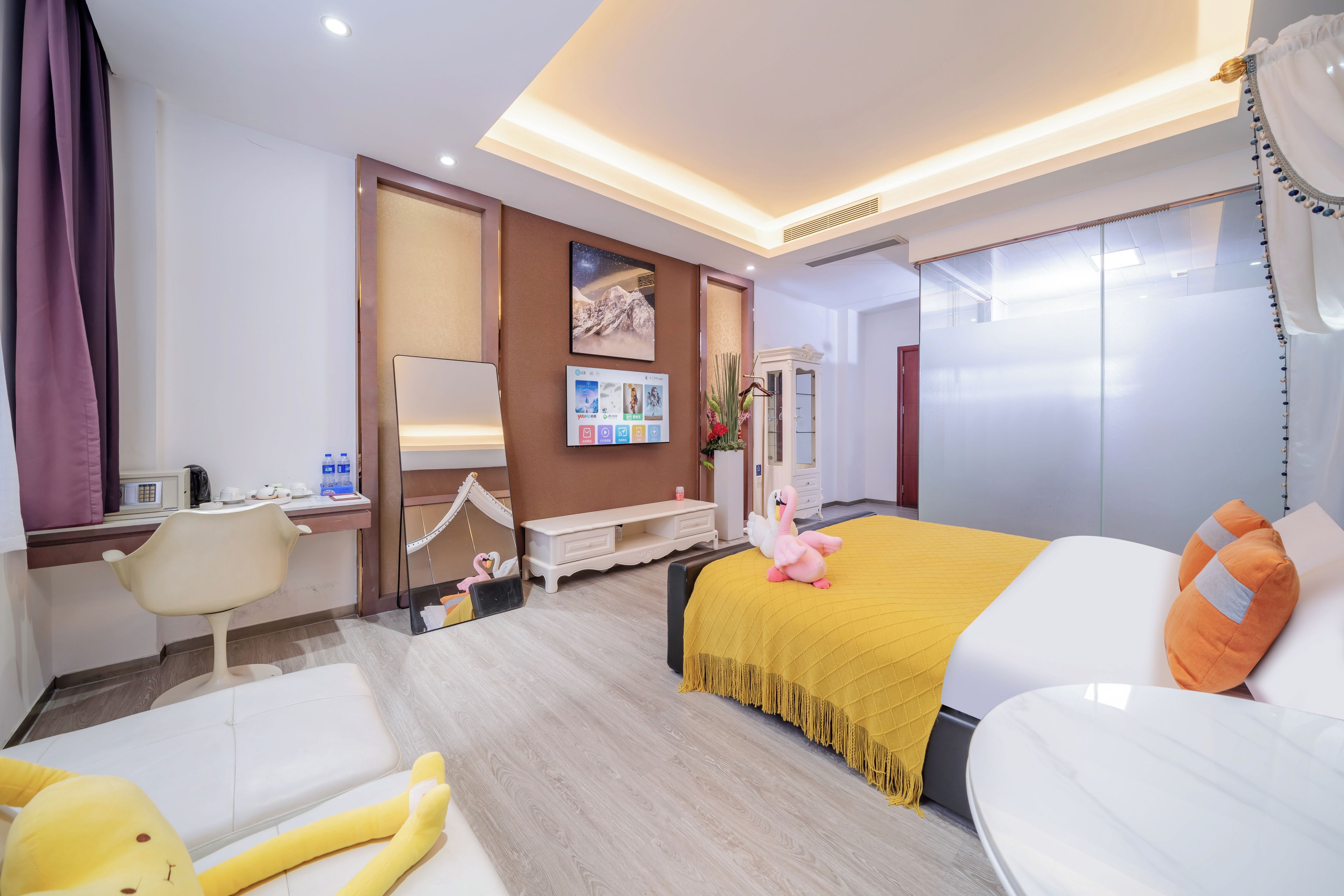 A hotel room with a bed, a desk, a chair, and a large mirror.