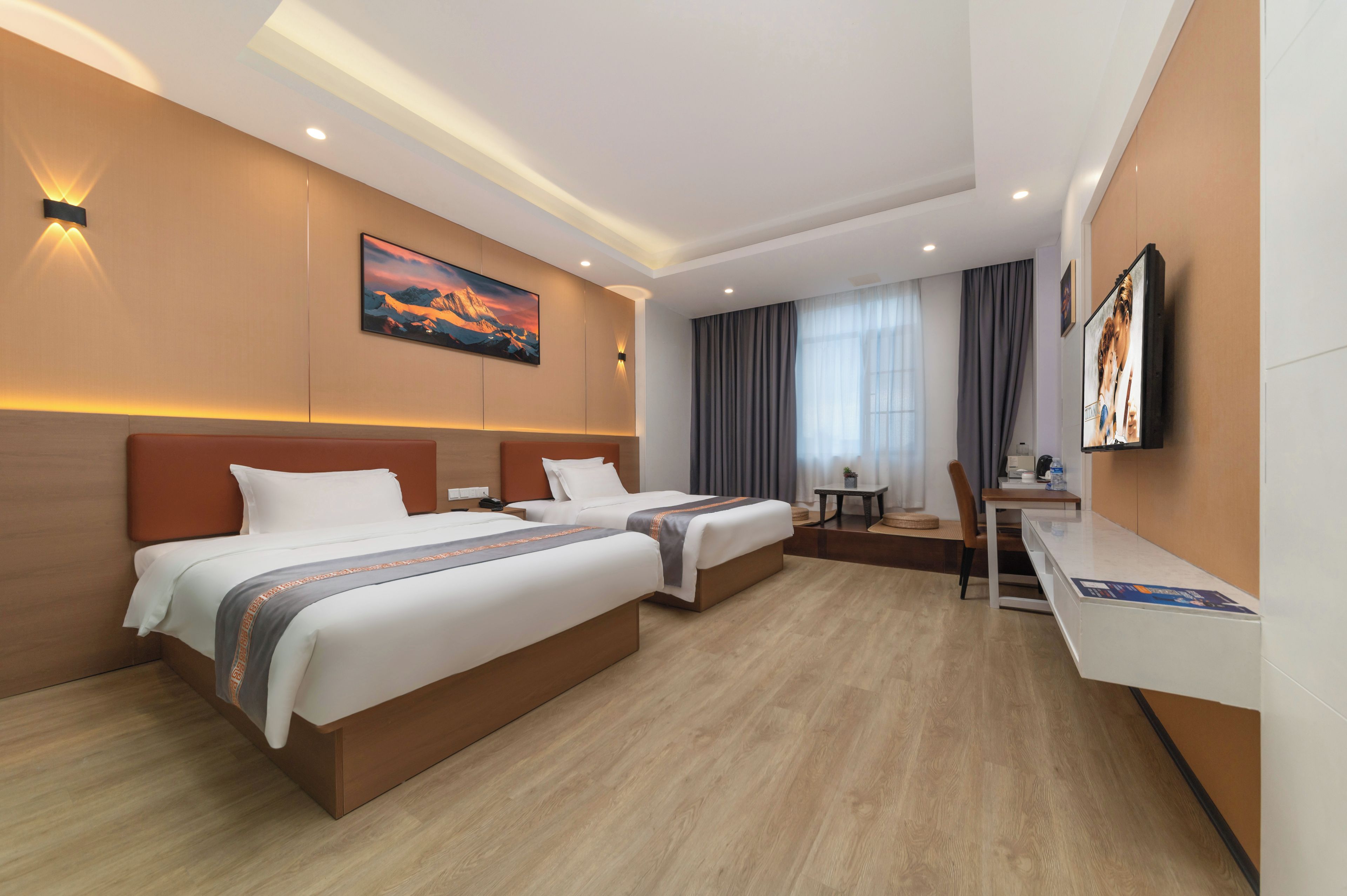 Quarto de hotel com duas camas, uma escrivaninha, uma cadeira, televisão e um quadro na parede.